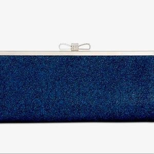 INC navy glitter clutch with rhinestone and silver bow clasp closure.